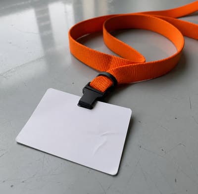 An orange event lanyard coiled on a table with a blank badge card.